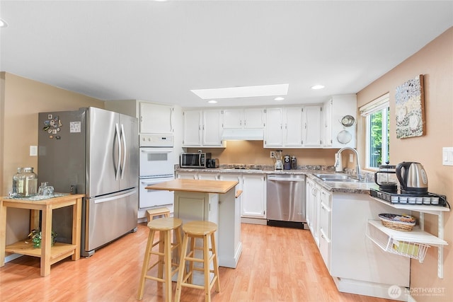3711 116th St SE, Everett, WA 98208 - kitchen featuring stainless steel appliances, a center island, light wood-style flooring, white cabinetry, and a skylight