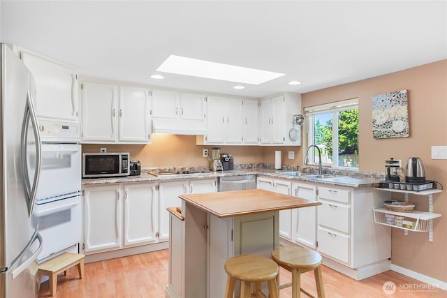 3711 116th St SE, Everett, WA 98208 - kitchen with appliances with stainless steel finishes, a skylight, light wood finished floors, white cabinets, and recessed lighting