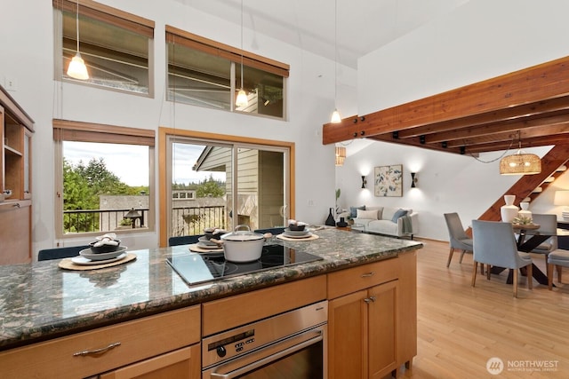 10036 NE 115th Ln Unit A3, Kirkland, WA 98033 - kitchen with stainless steel oven, beam ceiling, dark stone counters, light wood-style floors, and open floor plan