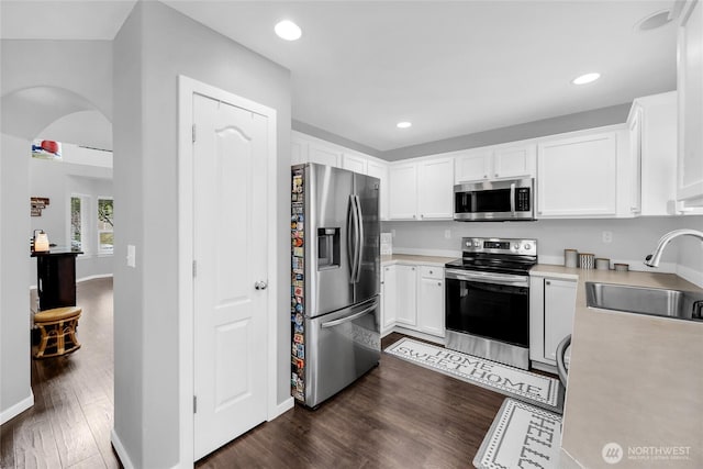 6815 278th St NW, Stanwood, WA 98292 - kitchen featuring stainless steel appliances, light countertops, dark wood-type flooring, white cabinetry, and arched walkways