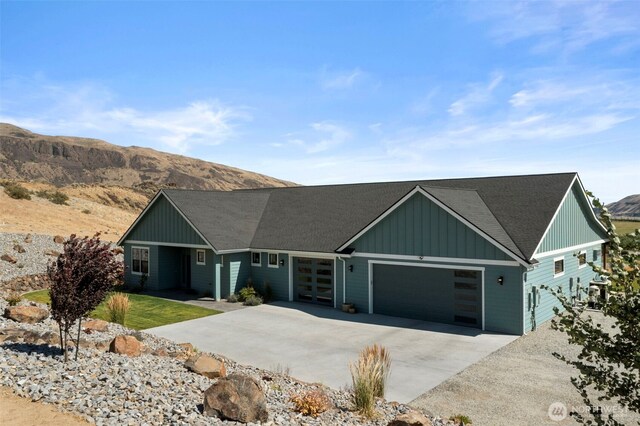 451S Partridge Ln, East Wenatchee, WA 98802 - view of front of house featuring board and batten siding, an attached garage, concrete driveway, a mountain view, and roof with shingles