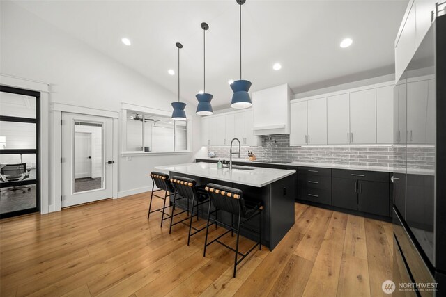 451S Partridge Ln, East Wenatchee, WA 98802 - kitchen featuring a breakfast bar area, light countertops, dark cabinetry, white cabinets, and decorative backsplash