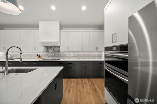 451S Partridge Ln, East Wenatchee, WA 98802 - kitchen featuring stainless steel appliances, white cabinetry, light wood-style flooring, dark cabinets, and decorative backsplash