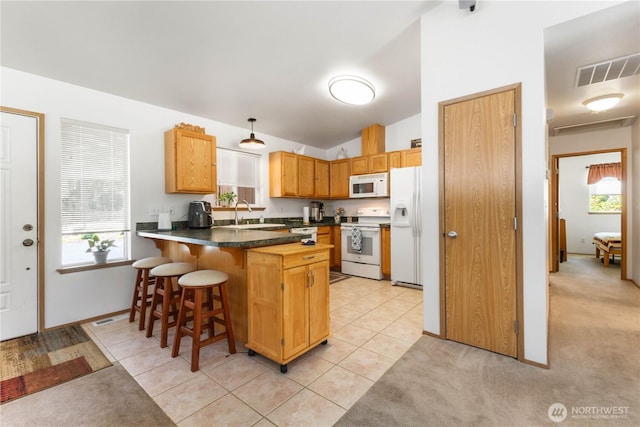 81 E Dunoon Pl, Shelton, WA 98584 - kitchen featuring a peninsula, white appliances, a breakfast bar area, dark countertops, and light tile patterned floors