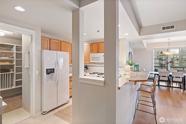 2801 1st Ave Unit 501, Seattle, WA 98121 - kitchen with white appliances, light countertops, a breakfast bar, light brown cabinetry, and a peninsula