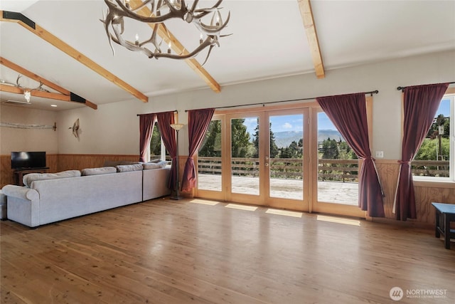 3613 Mcmullan Rd, Wenatchee, WA 98801 - unfurnished living room featuring a wainscoted wall, wood finished floors, wood walls, a chandelier, and french doors
