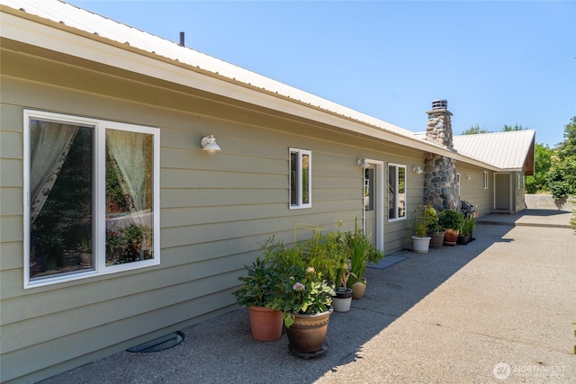 3613 Mcmullan Rd, Wenatchee, WA 98801 - view of home's exterior with a metal roof, a patio area, and a chimney