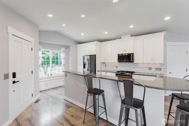 3761 Hannah Ct, Bellingham, WA 98226 - kitchen with stainless steel appliances, vaulted ceiling, backsplash, dark countertops, and light wood finished floors