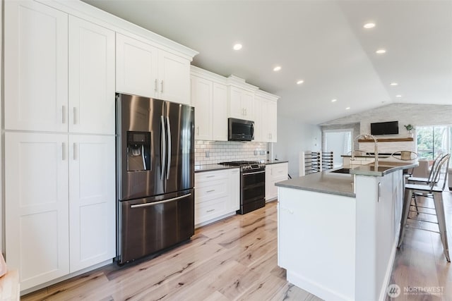 3761 Hannah Ct, Bellingham, WA 98226 - kitchen featuring stainless steel appliances, vaulted ceiling, light wood-style flooring, white cabinetry, and decorative backsplash