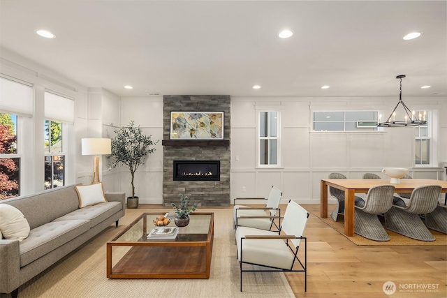 8841 Dibble Ave NW, Seattle, WA 98117 - living room featuring wood finished floors, a tiled fireplace, a chandelier, recessed lighting, and a decorative wall
