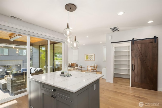 8841 Dibble Ave NW, Seattle, WA 98117 - kitchen featuring gray cabinetry, light wood-style flooring, a kitchen island, pendant lighting, and a barn door