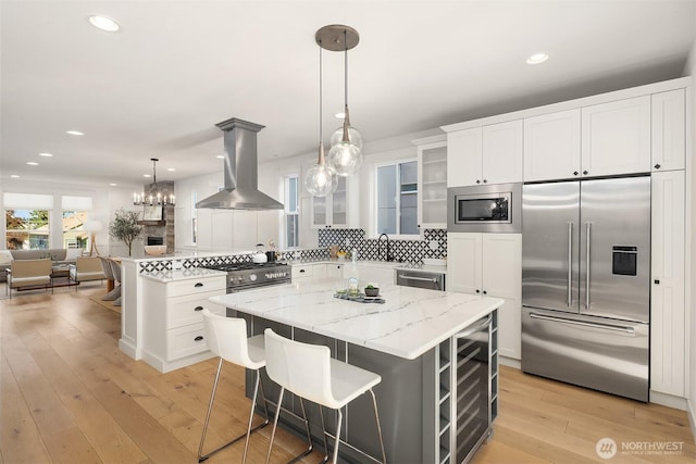 8841 Dibble Ave NW, Seattle, WA 98117 - kitchen with built in appliances, island range hood, glass insert cabinets, decorative backsplash, and light wood finished floors
