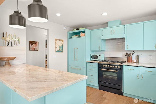 6002 Ridgeview Pl, Ferndale, WA 98248 - kitchen with black gas range oven, white microwave, blue cabinetry, paneled fridge, and recessed lighting