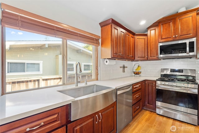 922 SW 160th St, Burien, WA 98166 - kitchen with stainless steel appliances, light countertops, decorative backsplash, light wood-style flooring, and brown cabinetry