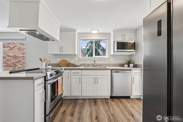 1022 N Anderson St, Tacoma, WA 98406 - kitchen with stainless steel appliances, custom exhaust hood, light wood-style flooring, white cabinetry, and a peninsula