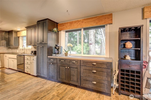 717 Judith Ct, Aberdeen, WA 98520 - kitchen featuring dishwasher, tasteful backsplash, light countertops, light wood-style floors, and healthy amount of natural light