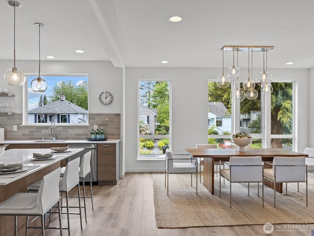 9015 Dibble Ave NW, Seattle, WA 98117 - kitchen featuring stainless steel dishwasher, decorative backsplash, light countertops, light wood-style flooring, and decorative light fixtures