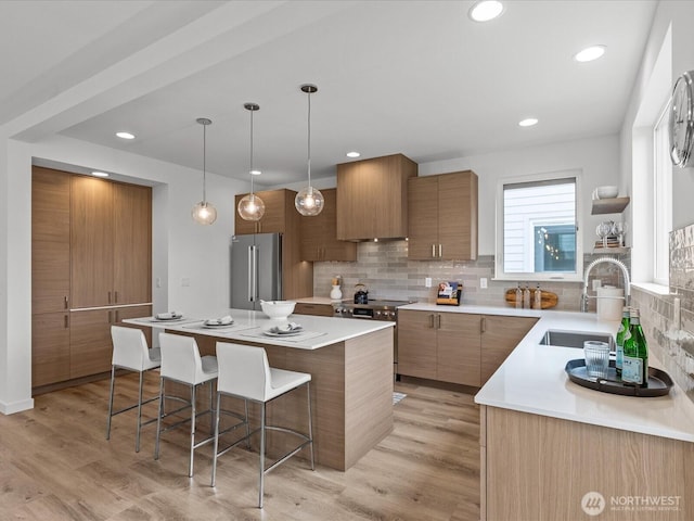 9015 Dibble Ave NW, Seattle, WA 98117 - kitchen with stainless steel appliances, a breakfast bar, decorative backsplash, a kitchen island, and brown cabinetry