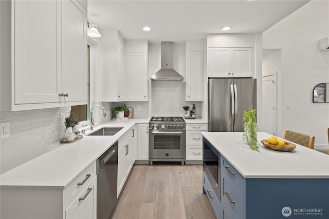 333 18th Ave, Kirkland, WA 98033 - kitchen featuring wall chimney range hood, appliances with stainless steel finishes, light countertops, white cabinetry, and light wood-type flooring