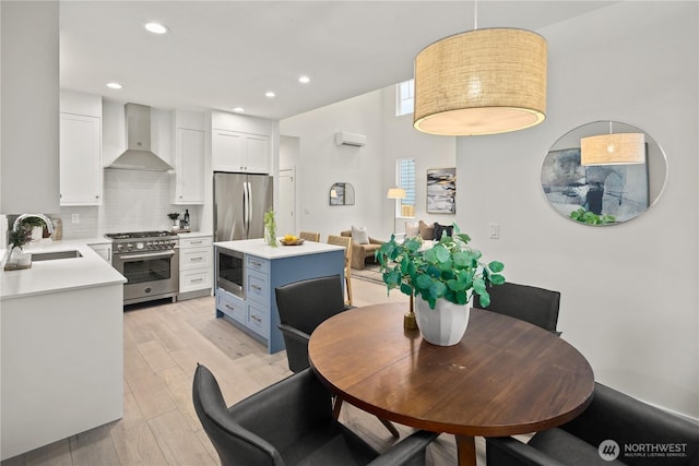 333 18th Ave, Kirkland, WA 98033 - kitchen featuring stainless steel appliances, wall chimney exhaust hood, white cabinets, light countertops, and light wood-type flooring