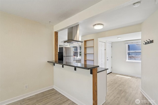 11303 Park Ave S, Tacoma, WA 98444 - kitchen with freestanding refrigerator, island exhaust hood, a peninsula, light wood finished floors, and a breakfast bar