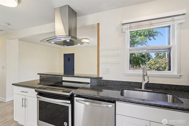 11303 Park Ave S, Tacoma, WA 98444 - kitchen featuring stainless steel appliances, island range hood, white cabinetry, dark stone counters, and light wood-style flooring