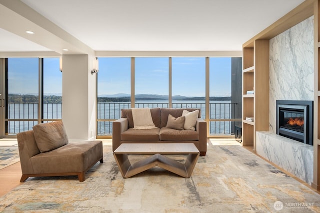 1620 43rd Ave E Unit 15A-B, Seattle, WA 98112 - living area with a water and mountain view, a wall of windows, a high end fireplace, recessed lighting, and wood finished floors