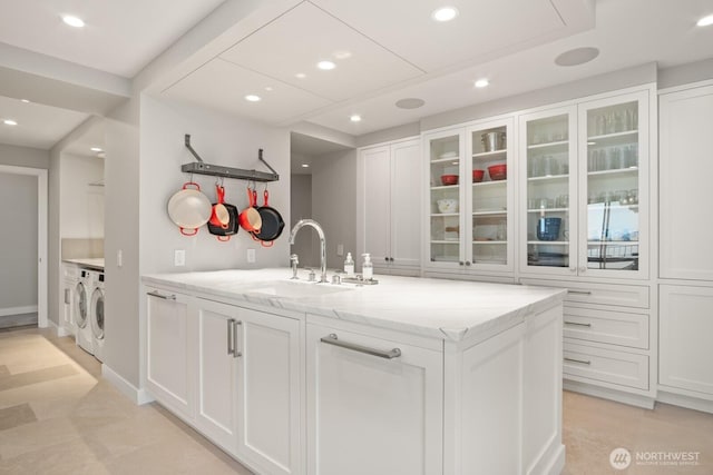 1620 43rd Ave E Unit 15A-B, Seattle, WA 98112 - kitchen with washer and clothes dryer, white cabinets, light stone counters, glass insert cabinets, and recessed lighting
