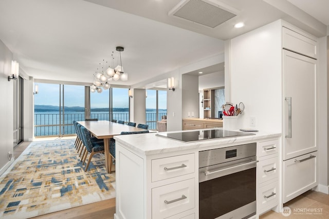 1620 43rd Ave E Unit 15A-B, Seattle, WA 98112 - kitchen featuring stainless steel oven, a water view, white cabinets, pendant lighting, and light stone countertops