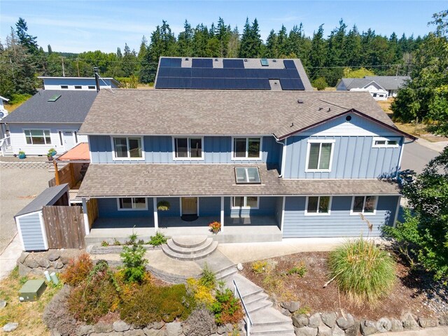 408 Eddy Ct, Port Townsend, WA 98368 - view of front of property featuring board and batten siding, covered porch, roof mounted solar panels, and a shingled roof