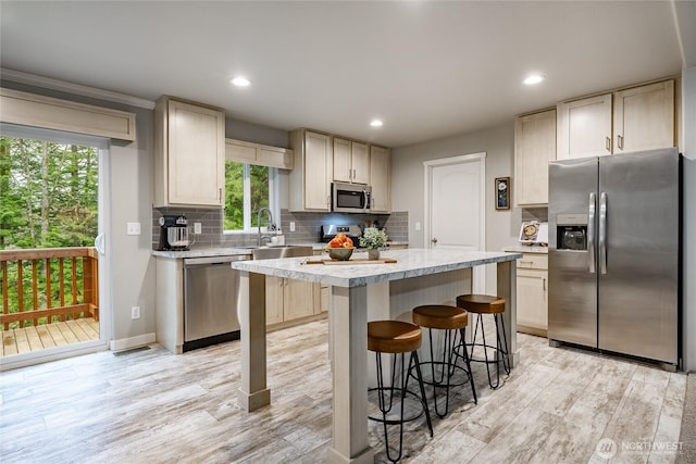 3563 Sweet Rd, Blaine, WA 98230 - kitchen featuring appliances with stainless steel finishes, light wood-type flooring, a center island, a kitchen breakfast bar, and backsplash