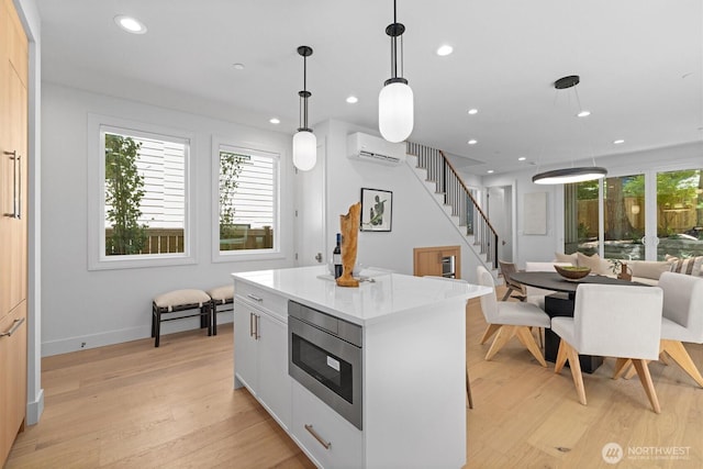 231 19th Ave, Kirkland, WA 98033 - kitchen with stainless steel microwave, a wall mounted air conditioner, light wood-style floors, recessed lighting, and a kitchen island