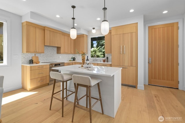 231 19th Ave, Kirkland, WA 98033 - kitchen with range, light wood-style flooring, a kitchen breakfast bar, decorative backsplash, and light countertops