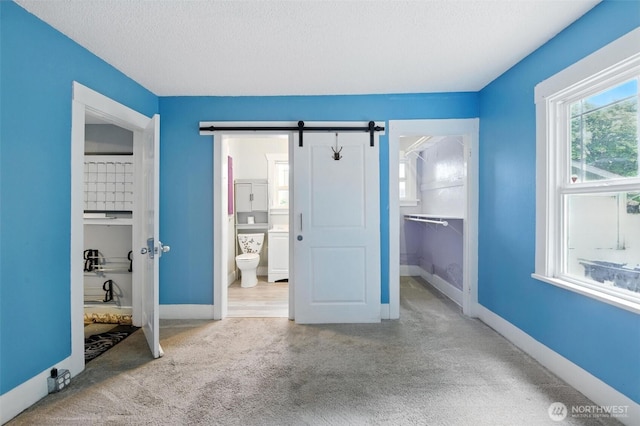 4061 E Howe St, Tacoma, WA 98404 - unfurnished bedroom with carpet, a walk in closet, a barn door, a textured ceiling, and ensuite bathroom