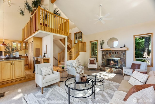6701 Macintosh Ct SE, Olympia, WA 98513 - living room featuring high vaulted ceiling, stairs, a fireplace, a ceiling fan, and light colored carpet