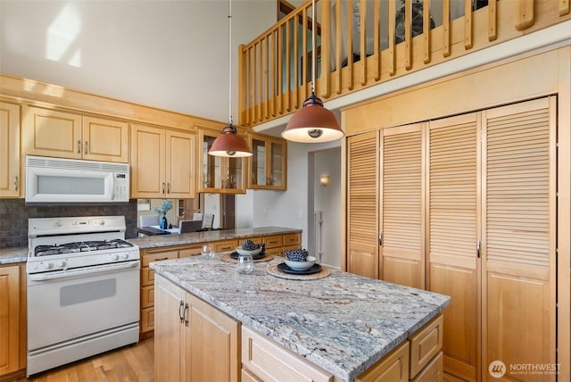 6701 Macintosh Ct SE, Olympia, WA 98513 - kitchen with white appliances, a center island, light brown cabinetry, glass insert cabinets, and a towering ceiling