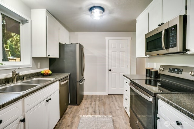 8106 186th Street Ct E, Puyallup, WA 98375 - kitchen with stainless steel appliances, dark countertops, light wood finished floors, and white cabinetry