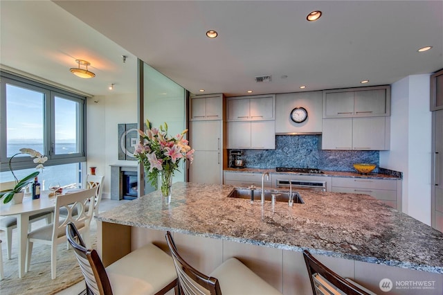 1521 2nd Ave Unit 2303, Seattle, WA 98101 - kitchen with tasteful backsplash, light stone countertops, recessed lighting, a breakfast bar, and gray cabinets