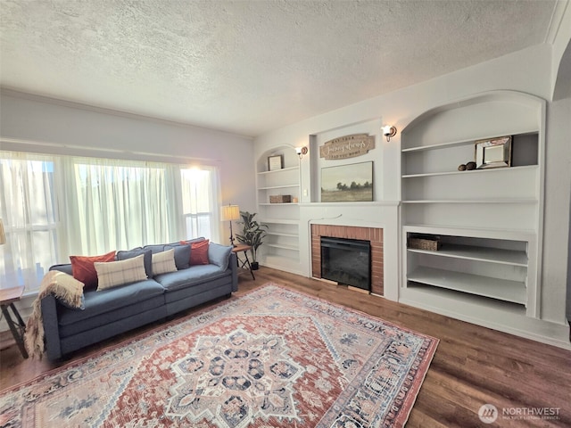321 12th St, Raymond, WA 98577 - living area featuring a textured ceiling, built in shelves, wood finished floors, and a brick fireplace