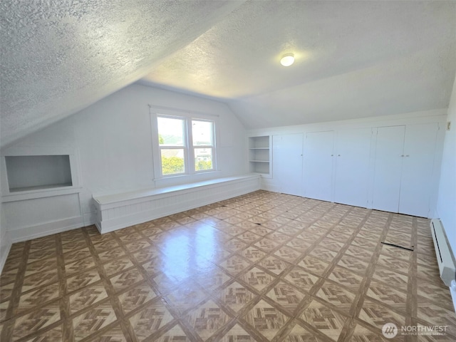 321 12th St, Raymond, WA 98577 - bonus room featuring lofted ceiling, a textured ceiling, built in shelves, and baseboard heating
