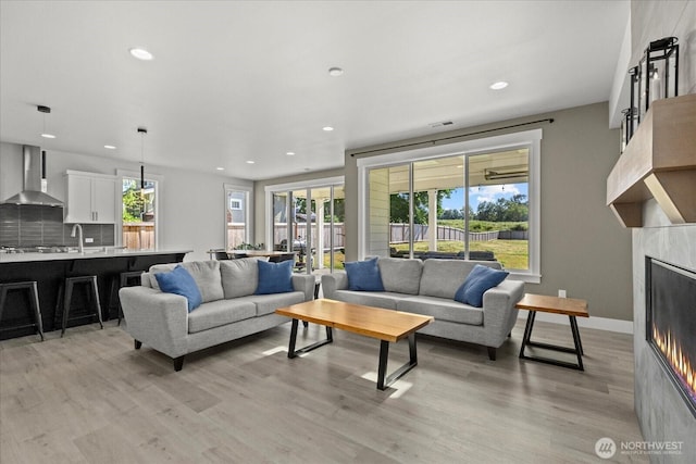 1427 114th Ave E, Edgewood, WA 98372 - living room featuring a warm lit fireplace, light wood-style floors, recessed lighting, and plenty of natural light