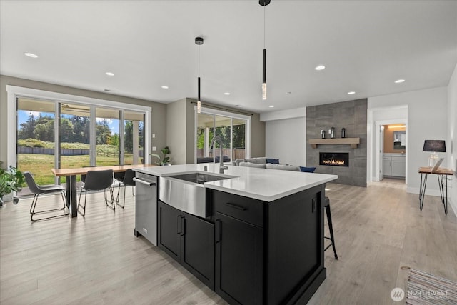 1427 114th Ave E, Edgewood, WA 98372 - kitchen with dark cabinets, a tile fireplace, light countertops, light wood-style flooring, and a center island with sink