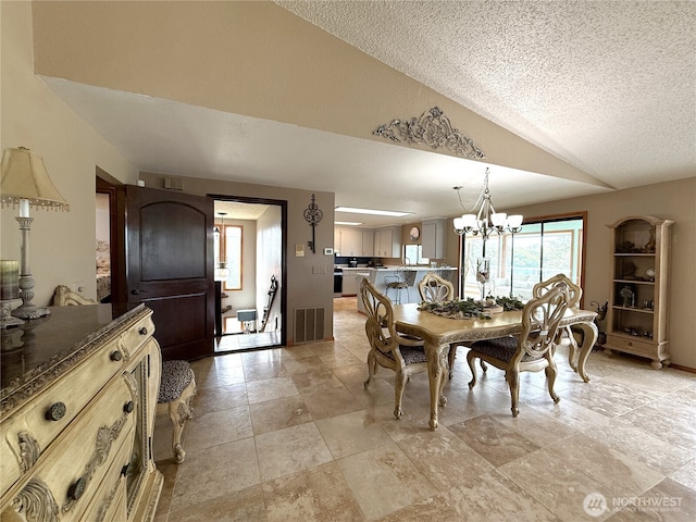 101 Sand Dune Ave NW, Ocean Shores, WA 98569 - dining space featuring lofted ceiling, a textured ceiling, a chandelier, and light stone finish flooring