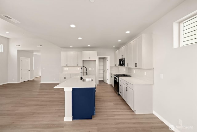 13931 178th St E Unit 39, Puyallup, WA 98374 - kitchen with stainless steel gas stove, backsplash, light wood-type flooring, light countertops, and recessed lighting