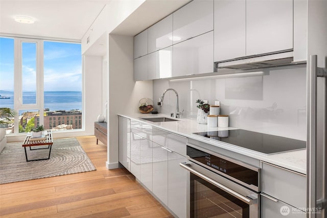 450 S Main St Unit 1608, Seattle, WA 98104 - kitchen with oven, black electric stovetop, modern cabinets, and under cabinet range hood