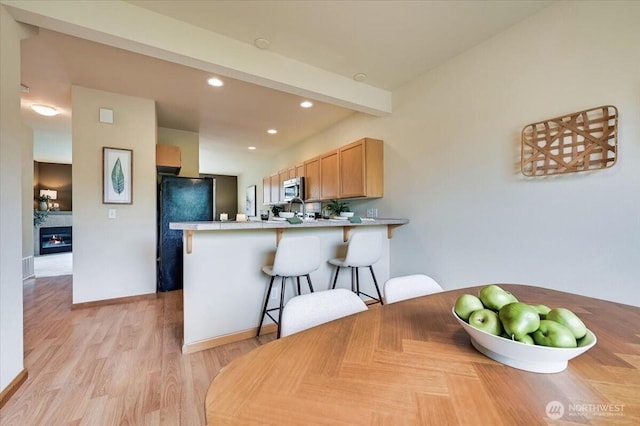 9411 18th Ave W Unit B, Everett, WA 98204 - kitchen featuring a peninsula, freestanding refrigerator, a kitchen bar, recessed lighting, and light wood-style flooring