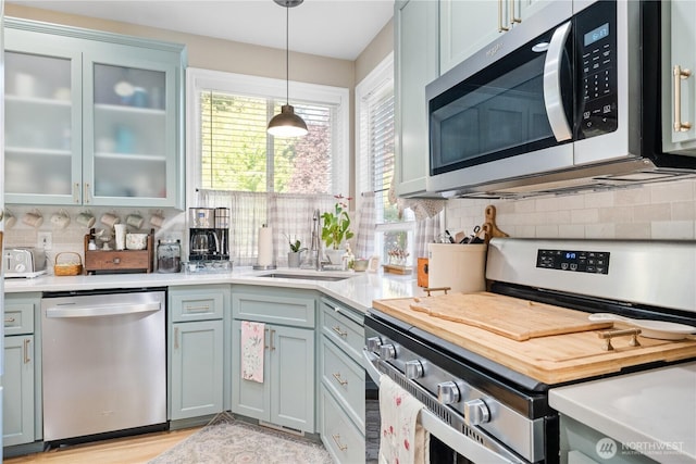 2060 Hammond Ave, Dupont, WA 98327 - kitchen with appliances with stainless steel finishes, light countertops, tasteful backsplash, hanging light fixtures, and glass insert cabinets