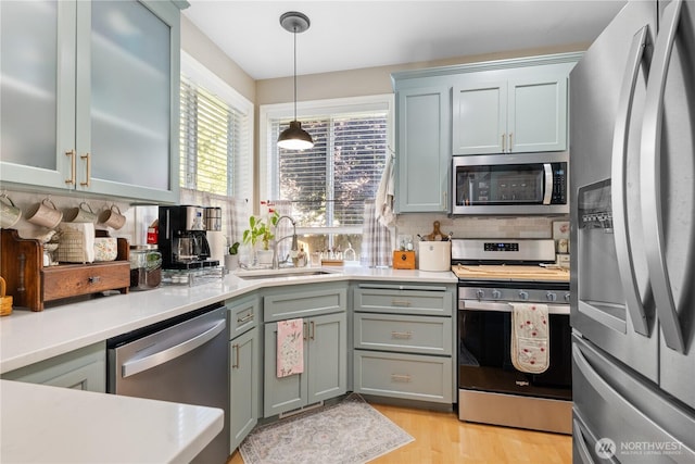 2060 Hammond Ave, Dupont, WA 98327 - kitchen featuring appliances with stainless steel finishes, light countertops, light wood-style floors, decorative light fixtures, and decorative backsplash