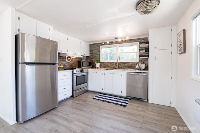 2500 Samish Way Unit 13, Bellingham, WA 98229 - kitchen with appliances with stainless steel finishes, white cabinets, under cabinet range hood, backsplash, and light wood-style floors