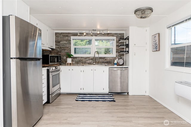 2500 Samish Way Unit 13, Bellingham, WA 98229 - kitchen with appliances with stainless steel finishes, white cabinetry, tasteful backsplash, and light wood-style floors
